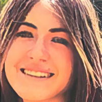 A close-up photograph of a young person with long brown hair smiling at the camera.