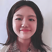 A woman with long dark hair smiling and wearing a checkered shirt, posed against a plain light background.